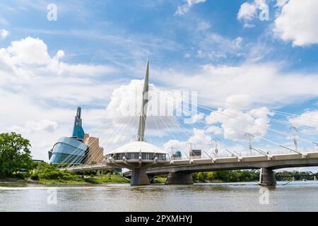 Il ponte pedonale Esplanade Riel attraversa il fiume Rosso nel centro di Winnipeg, Manitoba, accanto al simbolo del museo canadese per i diritti umani. Foto Stock