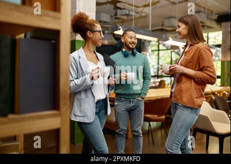 Diversi team di lavoro ridendo allegramente in ufficio coworking. Giovane businesspeople riuscito che prende la rottura corta durante il lavoro Foto Stock