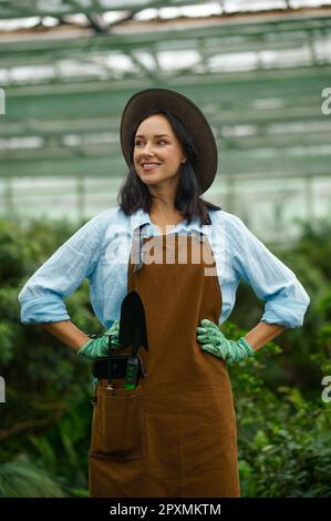 Ritratto di giovane donna felice imprenditore giardiniere indossando tute orgogliosa di bellezza della sua propria serra Foto Stock