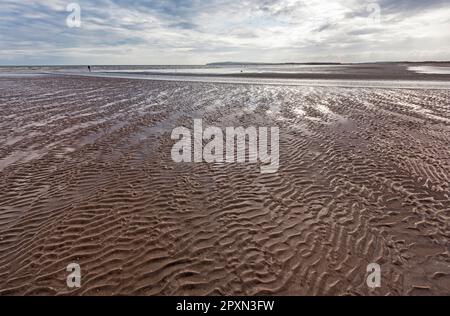 Solista su assolate e ventose Camber Sands a Rye Bay con la Manica sul confine del Sussex Kent e le formazioni nubi. Foto Stock