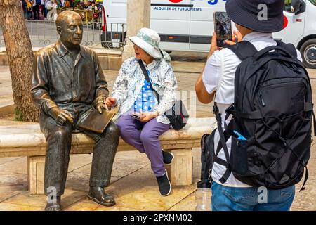 I turisti ammirano la statua in bronzo del 2008 di Pablo Picasso su una panchina in marmo di Francisco Lopez Hernandez in Plaza de la Merced Malaga Spagna. Foto Stock