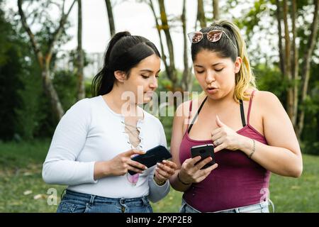 ragazze latina mostrandosi i messaggi di testo che hanno sui loro telefoni cellulari Foto Stock