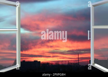Finestre di plastica che si affacciano sul bellissimo tramonto cremisi. Vista dalla finestra di casa aperta al tramonto. Tramonto Crimson fuori dalla finestra. Sera fuori Foto Stock
