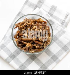 Ciotola di vetro piena di funghi selvaggi congelati miele agarici su tovagliolo a scacchi su sfondo bianco. Cibo biologico sano. Il congelamento preserva perfettamente Foto Stock