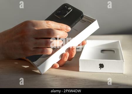 Lodz, Polonia Aprile 30 2023 mani prendendo il nuovo modello nero di Apple iphone 14 pro max dalla scatola. Foto Stock