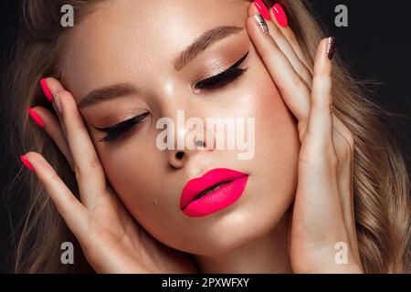 Bella giovane donna con brillante trucco e neon pink chiodi. Bellezza viso. Foto scattata in studio. Foto Stock