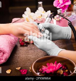 Cura delle unghie del dito del primo piano da specialista di manicure in salone di bellezza. Utensile elettrico professionale per manicure e pedicure. Foto Stock