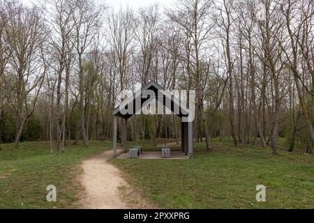 Un piccolo gazebo in un parco con alberi e un sentiero che porta a sinistra. Foto Stock