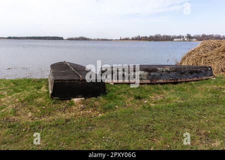 Una piccola barca si posò capovolta sull'erba accanto al lago. Foto Stock