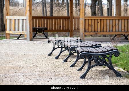 Una fila di panchine su un patio con una struttura in legno sullo sfondo. Foto Stock