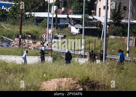 Ramallah, vicino all'insediamento ebraico di Beit El, nella Cisgiordania occupata il 02 maggio 2023. I giovani palestinesi gettano pietre durante gli scontri con i solidari israeliani a seguito della morte del prigioniero palestinese Khader Adnan, morto dopo uno sciopero della fame di 87 giorni in una prigione israeliana, all'ingresso nord della città di Ramallah, vicino all'insediamento ebraico di Beit El, Nella Cisgiordania occupata il 02 maggio 2023. Credit: UPI/Alamy Live News Foto Stock