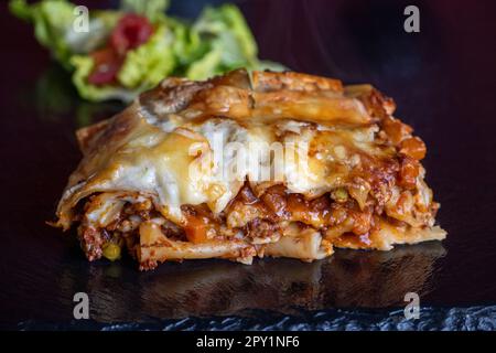 porzione di lasagna su ardesia nera Foto Stock
