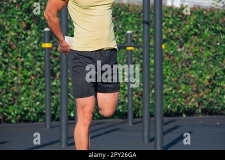 Il riscaldamento stretching esegue le gambe di un uomo sul terreno sportivo Foto Stock