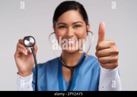 Dimentica di essere una principessa, im un medico. Ritratto di un giovane medico che mostra i pollici in su e che tiene uno stetoscopio su uno sfondo bianco. Foto Stock