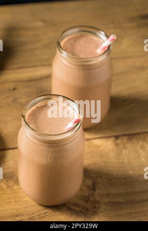 Proteina di siero di latte al cioccolato dolce congelato agitare con banana e latte Foto Stock