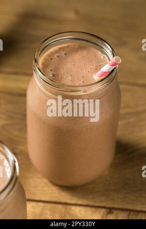 Proteina di siero di latte al cioccolato dolce congelato agitare con banana e latte Foto Stock