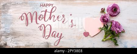 Biglietto d'auguri per il giorno della mamma con fiori di ranuncolo viola su legno d'annata. Sfondo orizzontale con testo in inglese. Vista dall'alto. Foto Stock