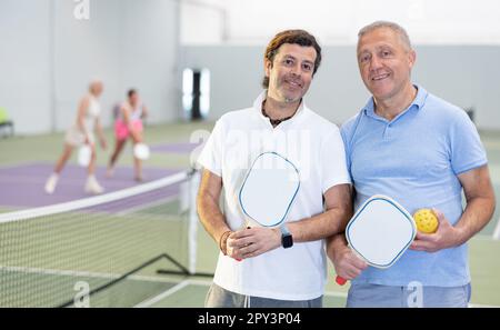 Due giocatori maschi di pickleball in piedi sul campo interno Foto Stock