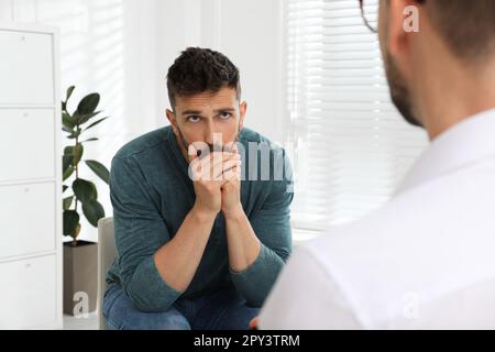 Psicoterapeuta che lavora con l'uomo tossicodipendente al chiuso Foto Stock