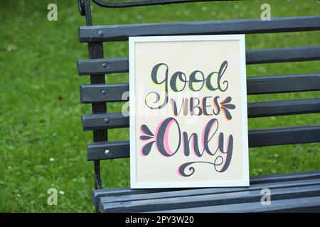 Poster con frase Good Vibes solo su panca di legno nero all'aperto Foto Stock