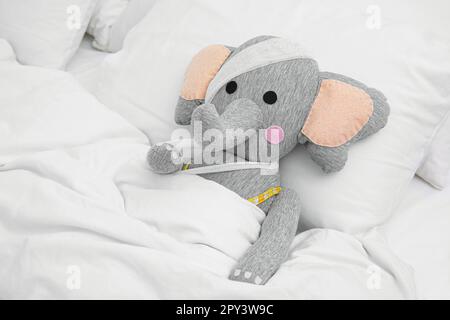 Elefante giocattolo con bende sdraiate a letto Foto Stock