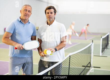 Due giocatori maschi di pickleball in piedi sul campo interno Foto Stock