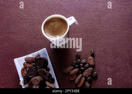 Tazza di caffè con cioccolatini fotografati su sfondo marrone dipinto Foto Stock