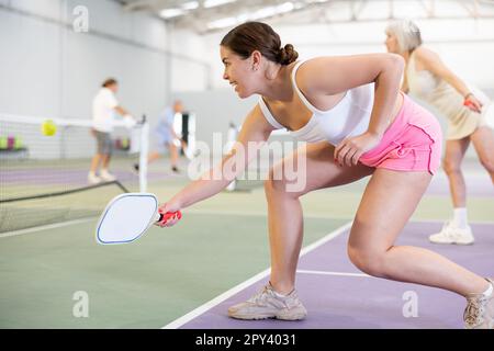 Giovane ragazza concentrata pickleball giocatore in attesa di ricevere servizio Foto Stock