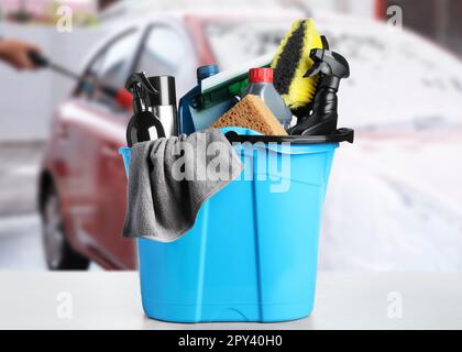 Secchio con rifornimenti di pulizia sul tavolo al lavaggio auto Foto Stock