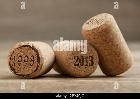 Tappi di vino con date diverse su tavola di legno, primo piano Foto Stock