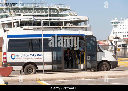 Candia, Creta, Grecia, UE. 2023. Un autobus cittadino di Heraklion in attesa di passeggeri nel porto con un backgrounf di traghetti. Foto Stock