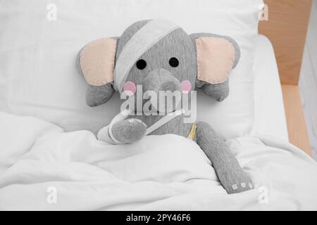 Elefante giocattolo con bende sdraiate a letto Foto Stock