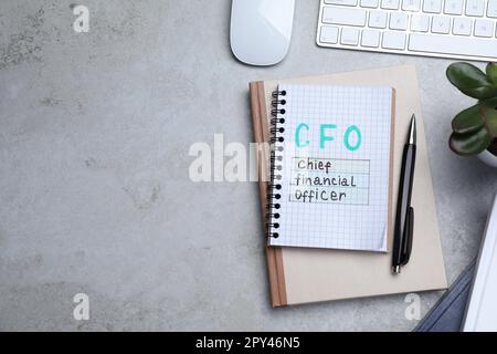 Notebook con abbreviazione CFO e spazio per testo su tavolo grigio da ufficio, piano di appoggio. Gestione finanziaria Foto Stock