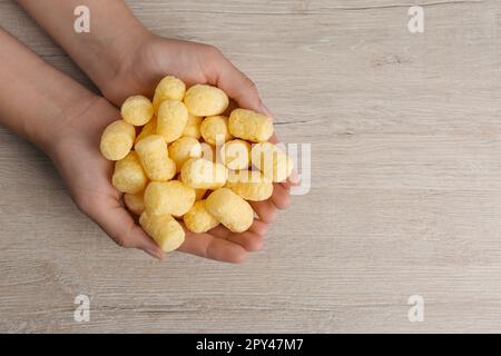 Donna che tiene bastoni di mais al tavolo di legno, vista dall'alto Foto Stock