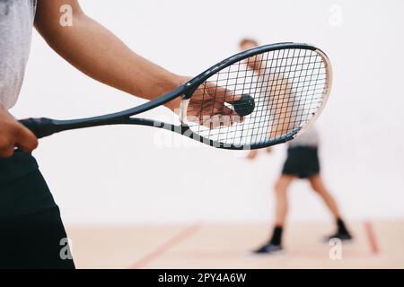 Il suo tutto nel modo in cui si serve. un uomo che serve una palla con una racchetta durante una partita di squash. Foto Stock