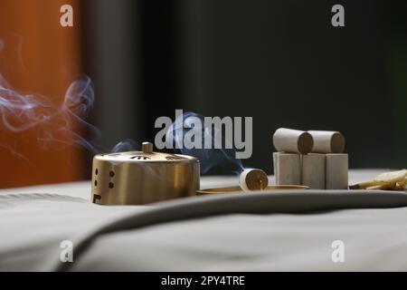 Trattamento di moxibustion - attrezzi cinesi tradizionali della medicina per la terapia di riscaldamento dei punti di agopuntura. Medicina cinese di erbe. Bruciatore in rame Moxibustion Foto Stock