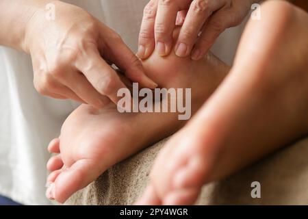 Cliente che riceve un trattamento di riflessologia di acupressione con bastoncino massaggiatore a punta di legno. Medicina naturale, riflessologia, massaggio ai piedi dell'acupressione Foto Stock