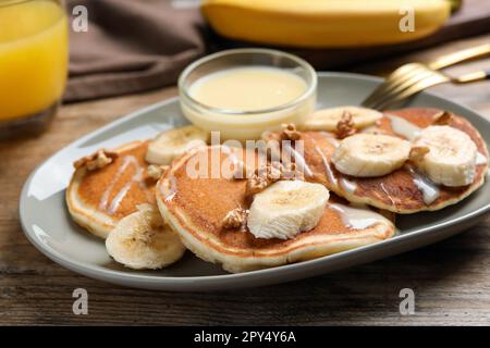 Gustose frittelle con banana a fette servite su tavolo di legno, primo piano Foto Stock