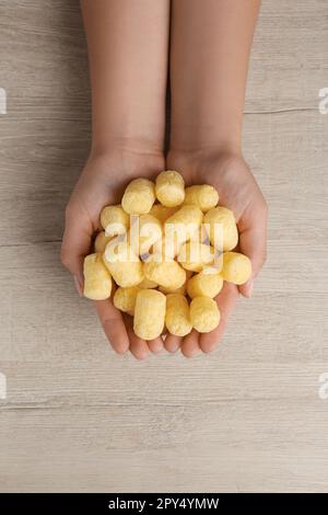 Donna che tiene bastoni di mais al tavolo di legno, vista dall'alto Foto Stock