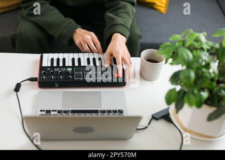 Vista dall'alto del produttore musicale o dell'arrangiatore utilizzando un computer portatile e una tastiera Midi e altre apparecchiature audio per creare musica nello studio di casa. Crea e organizza contenuti audio e comporre il concetto di canzone Foto Stock