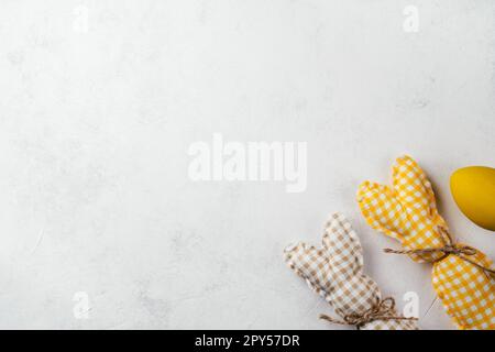 Cartolina di Pasqua per festeggiamenti, due coniglietti quadrati fatti a mano e uovo di gallina giallo su sfondo bianco Foto Stock