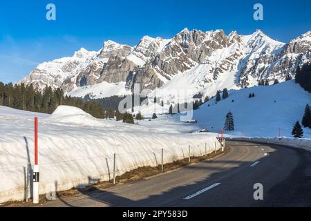 Strada di montagna nelle Alpi svizzere con vista panoramica sul massiccio Alpstein e sulla vetta del Saentis in inverno, regione del Toggenburg, Canton Sankt Gallen, Svizzera Foto Stock