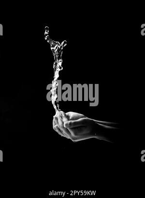 Mani di donna con spruzzi d'acqua su sfondo nero Foto Stock