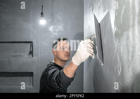 l'uomo applica l'isolamento alla parete di un bagno Foto Stock