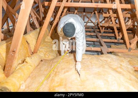 taglio di lana di vetro quando si isola il soffitto sul tetto Foto Stock
