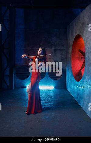 Violinista femminile che si esibisce sul palco grange per fotocamera Foto Stock