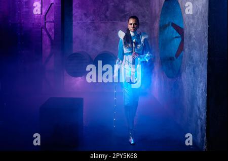 Giovane donna che gioca violino al neon su sfondo fumé blu Foto Stock