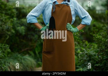 Primo piano donna giardiniere in tute con utensile da giardino in tasca Foto Stock