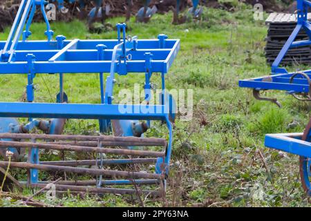 Le attrezzature agricole pesanti blu come l'aratro con dischi in acciaio affilato per la coltivazione agricola su campo con attrezzature trainate da trattore per la preparazione del lavoro sul campo facilitano la meccanizzazione del lavoro agricolo duro Foto Stock