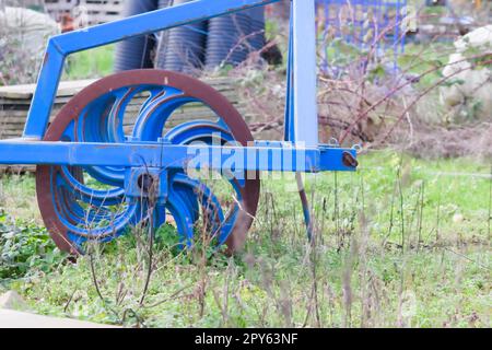 Le attrezzature agricole pesanti blu come l'aratro con dischi in acciaio affilato per la coltivazione agricola su campo con attrezzature trainate da trattore per la preparazione del lavoro sul campo facilitano la meccanizzazione del lavoro agricolo duro Foto Stock